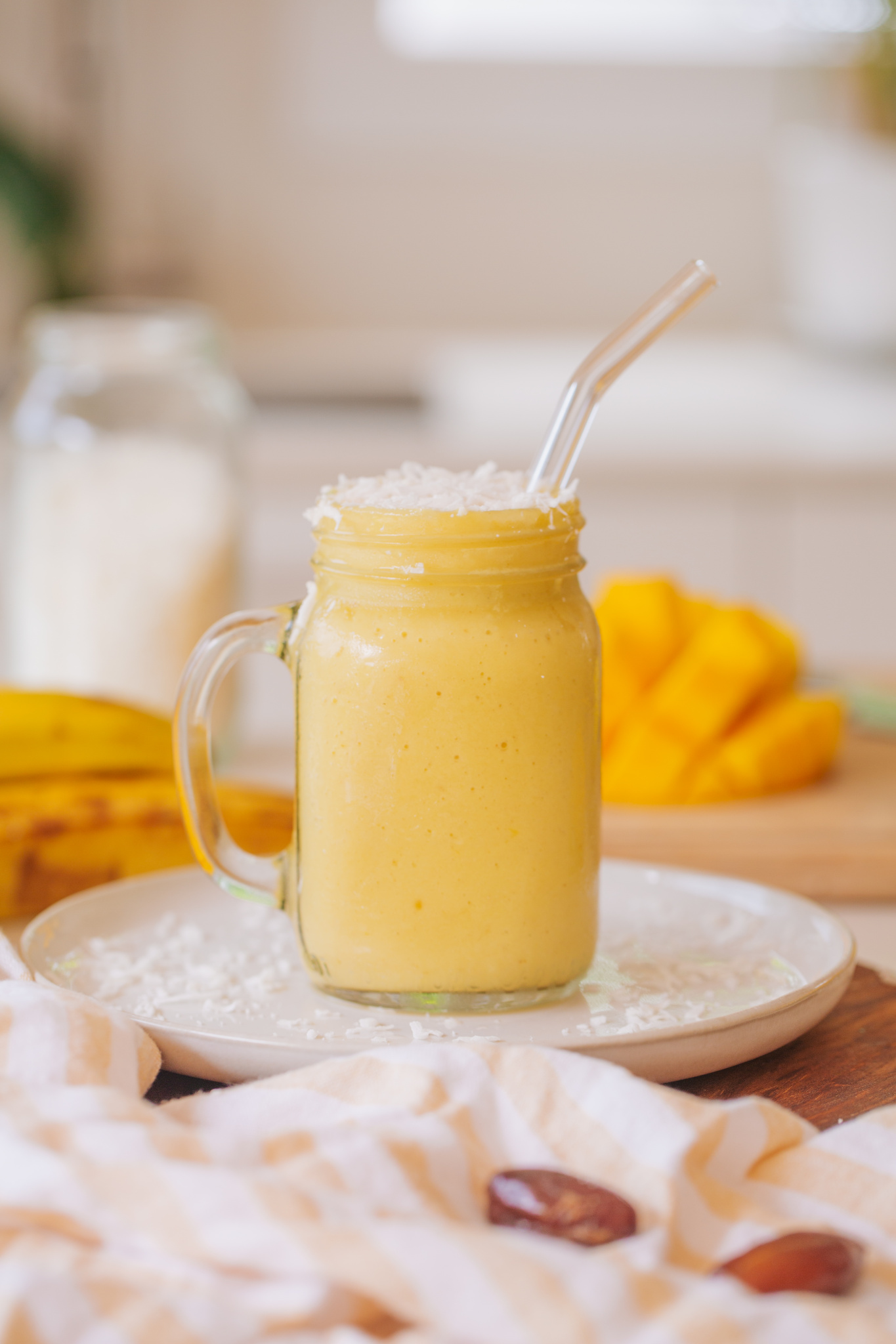 mango and banana sunshine smoothie with coconut on top of white plate