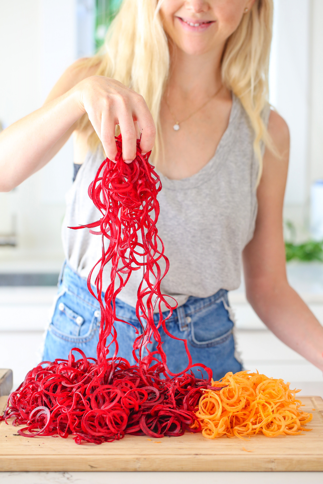 Beetroots and carrots spiral cut on a light brown chopping board. Buffy Ellen shown holding a handful of the beetroots 