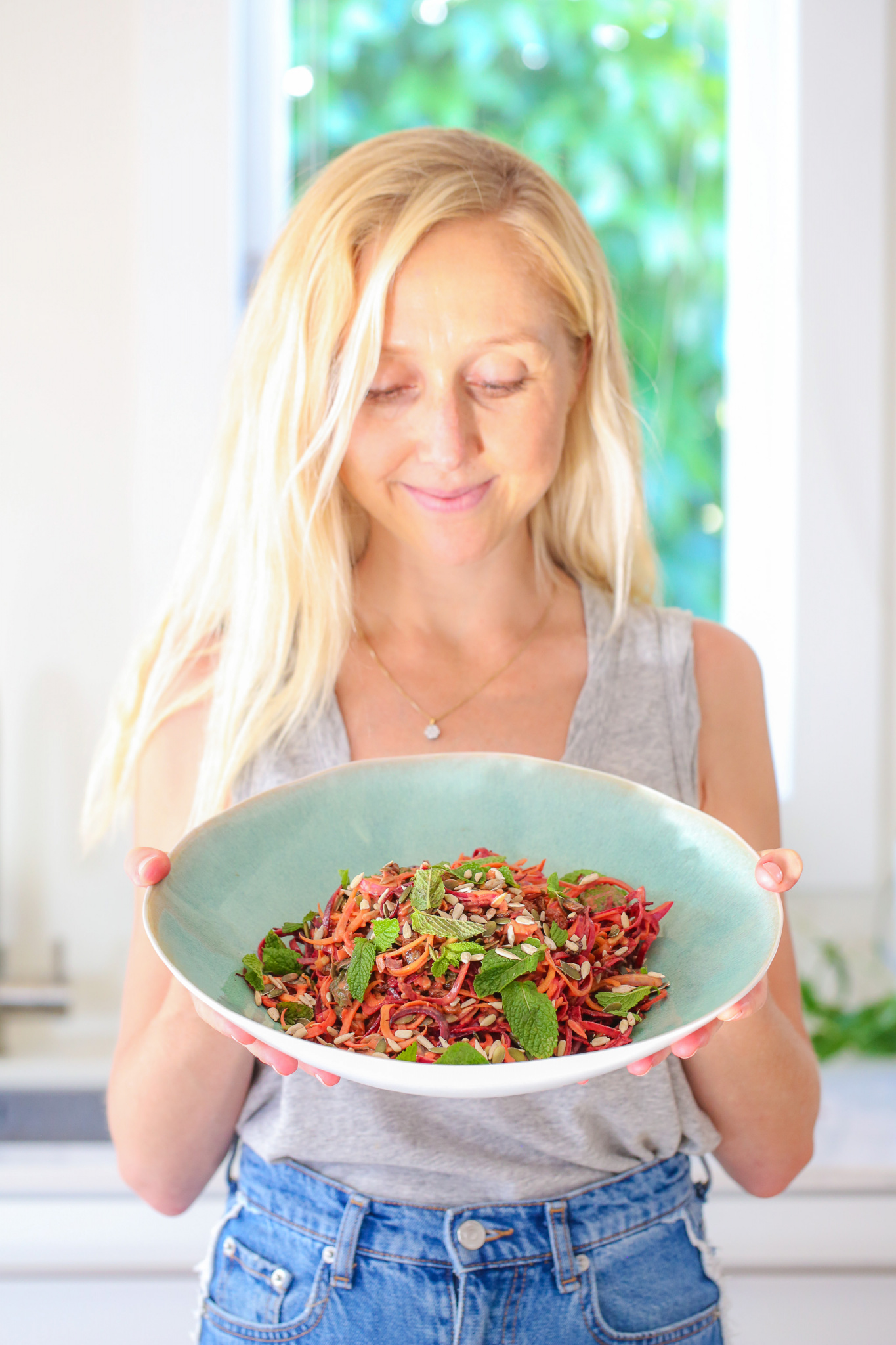 Raw Beetroot Salad in a while bowl (blue interior). Buffy Ellen shown holding the bowl. 