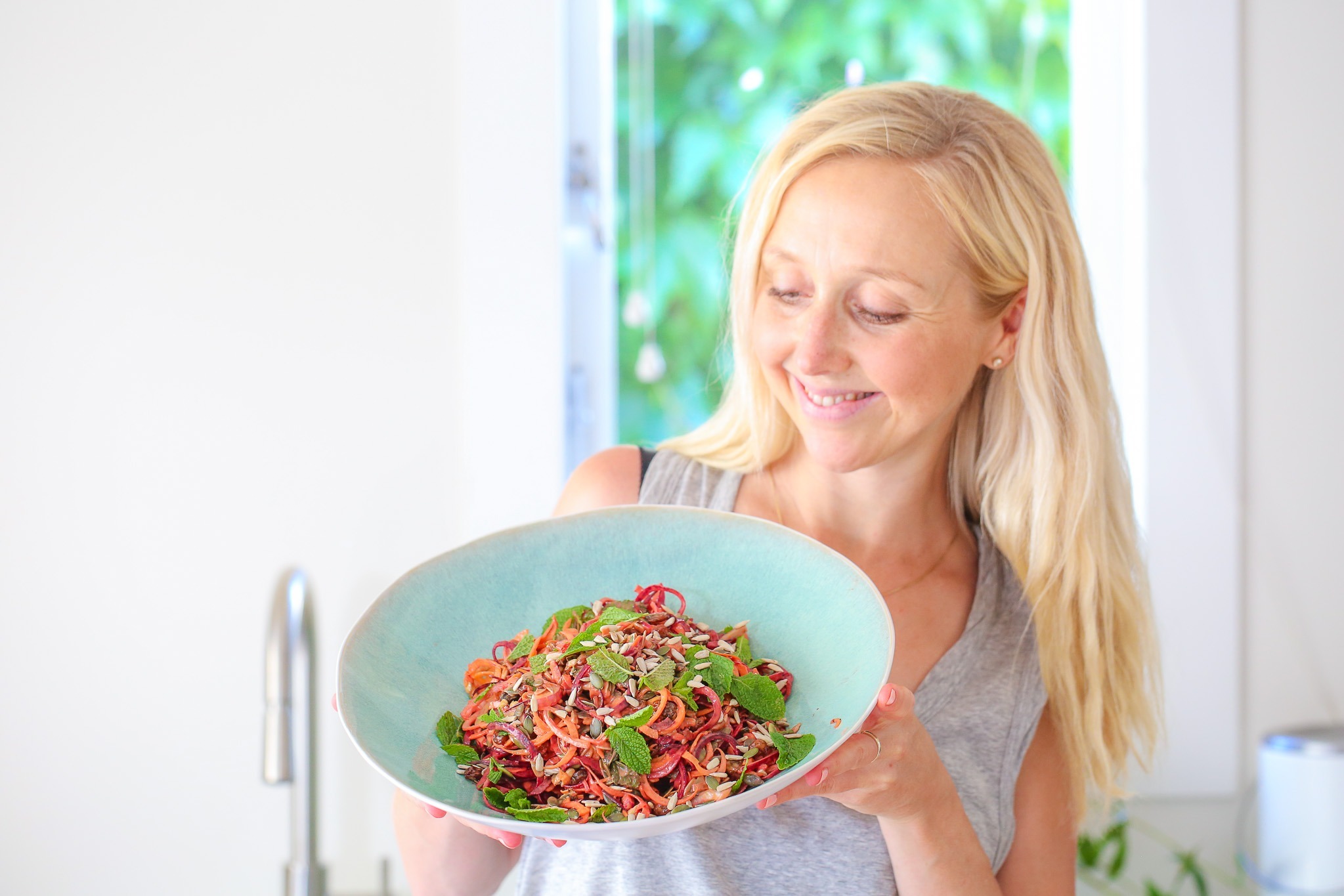 Raw Beetroot Salad in a while bowl (blue interior). Buffy Ellen shown holding the bowl. 