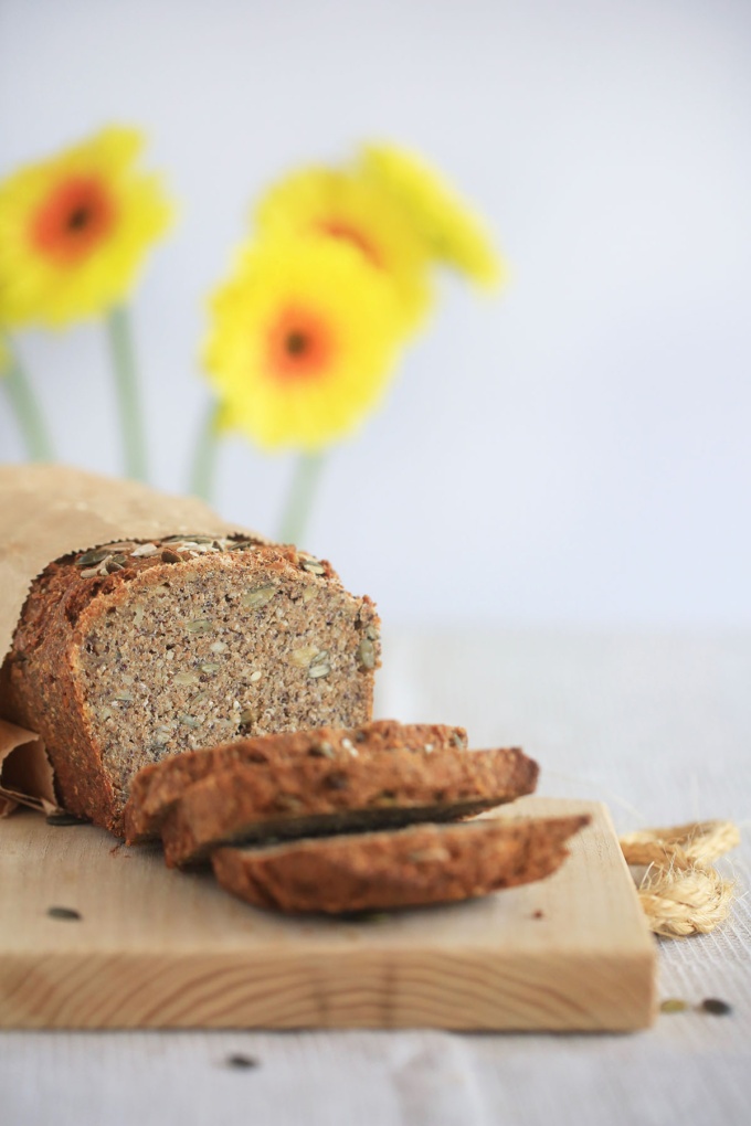 sliced vegan five seed sourdough bread with sunflowers in background from side