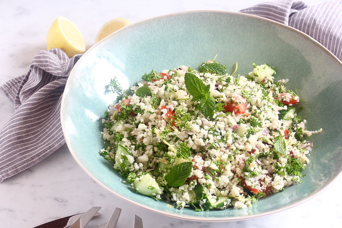 auliflower tabouli on white bench with salad tongs