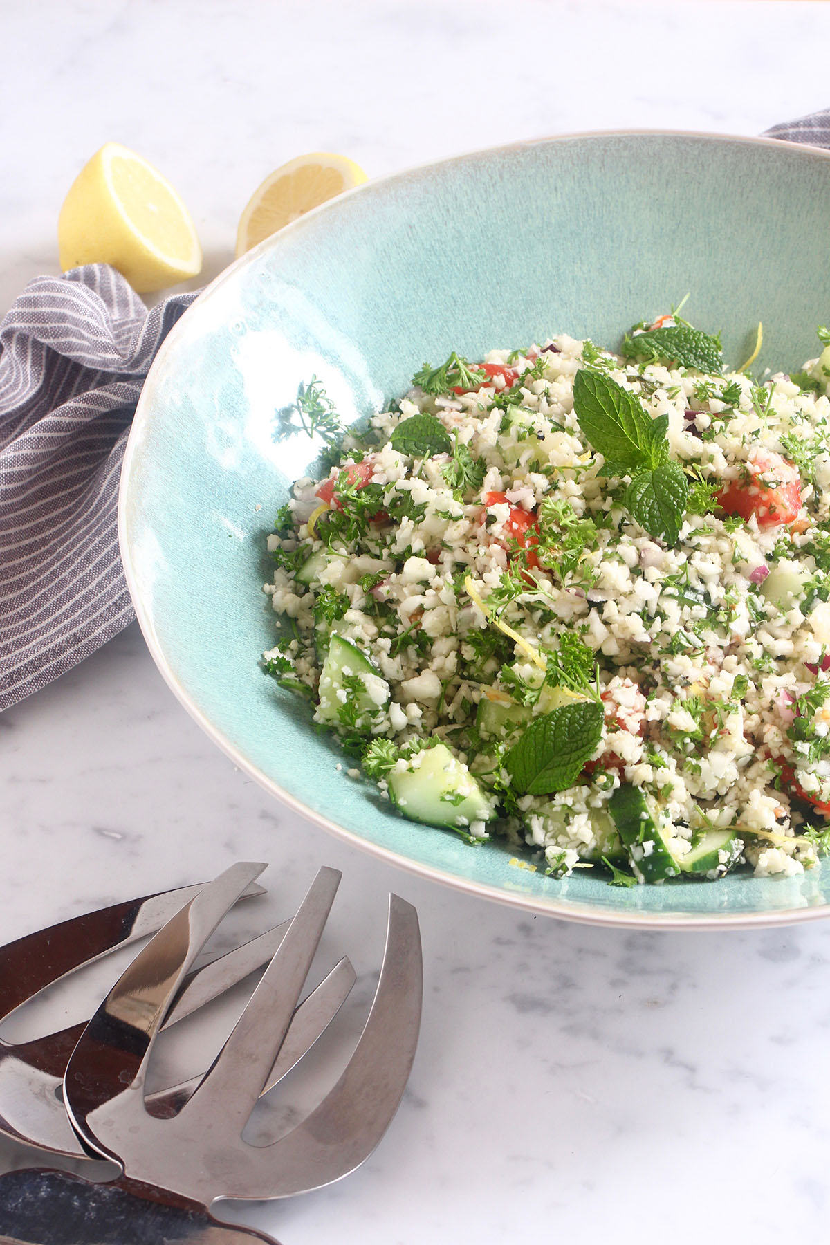 side front cauliflower tabouli on white bench with salad tongs