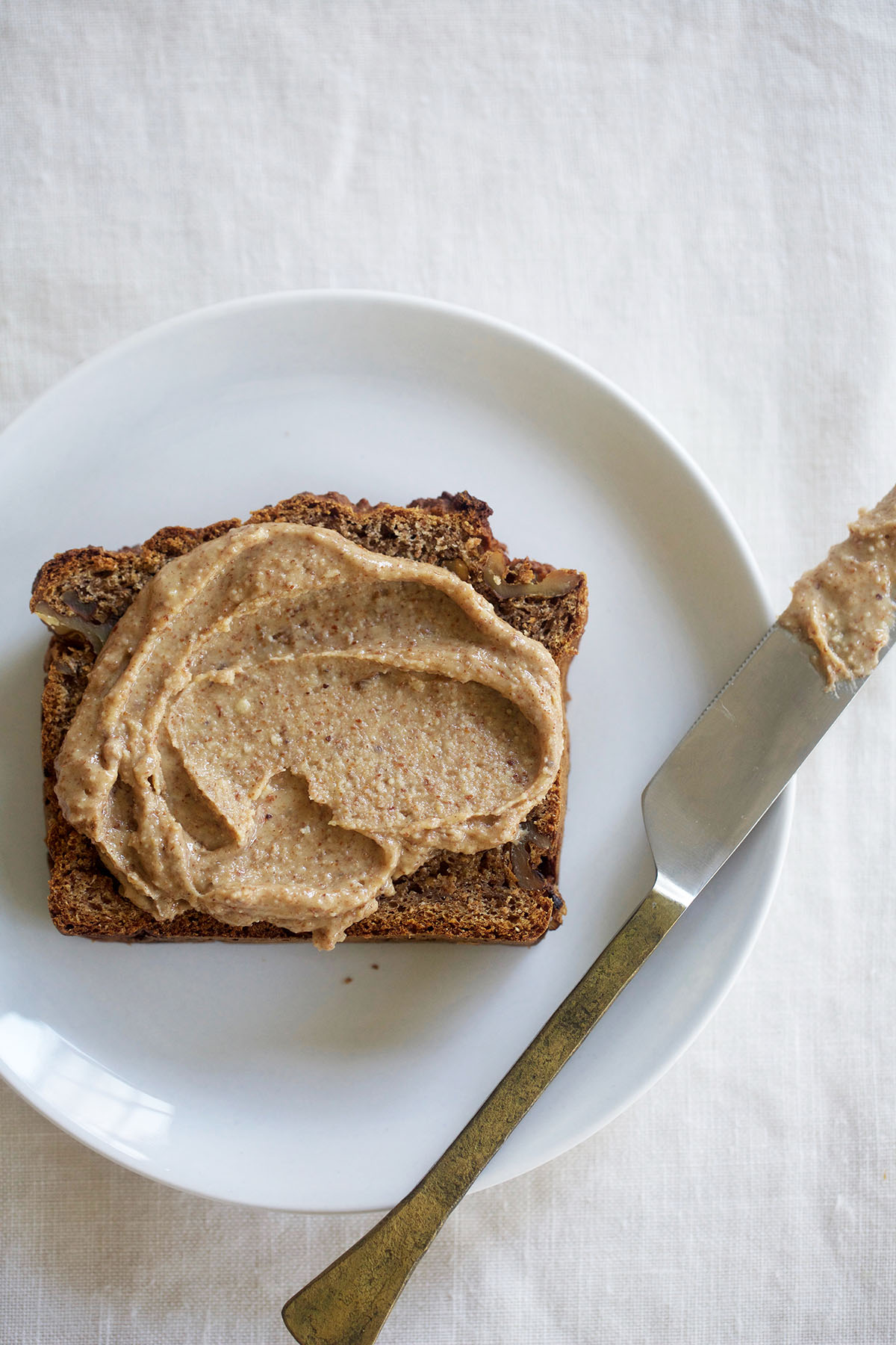 healthy walnut banana bread with nut butter spread on white plate