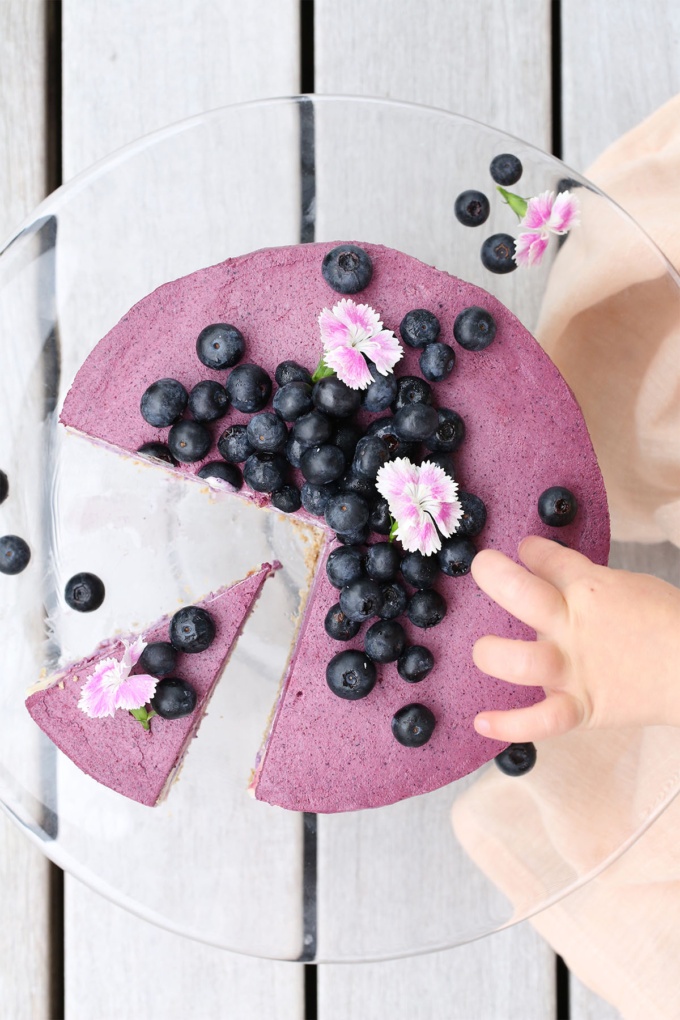 Childs hand reaching for vegan blueberry and beetroot cheesecake 