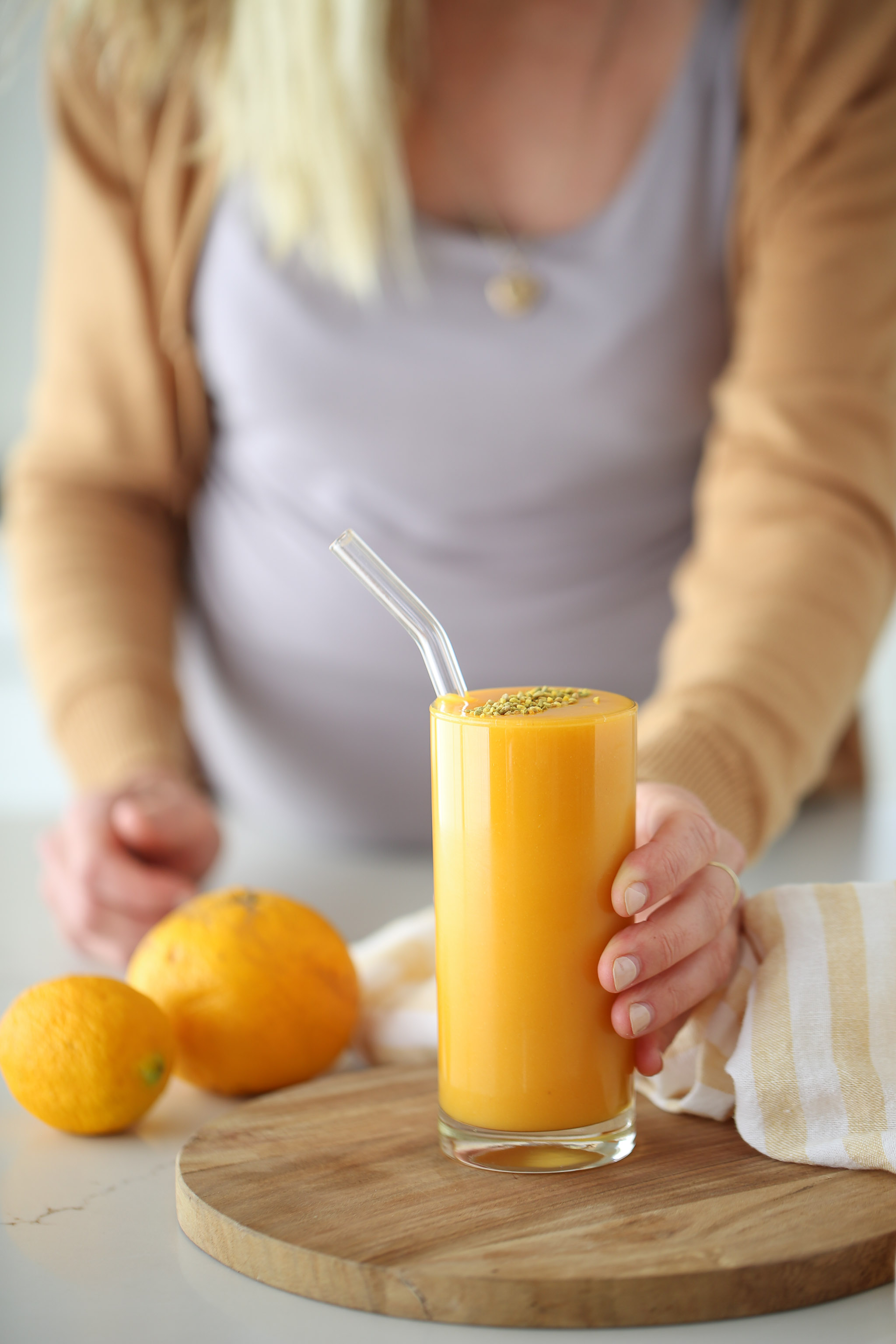 Glass of a flu shot smoothie with orange and lemon and a glass straw