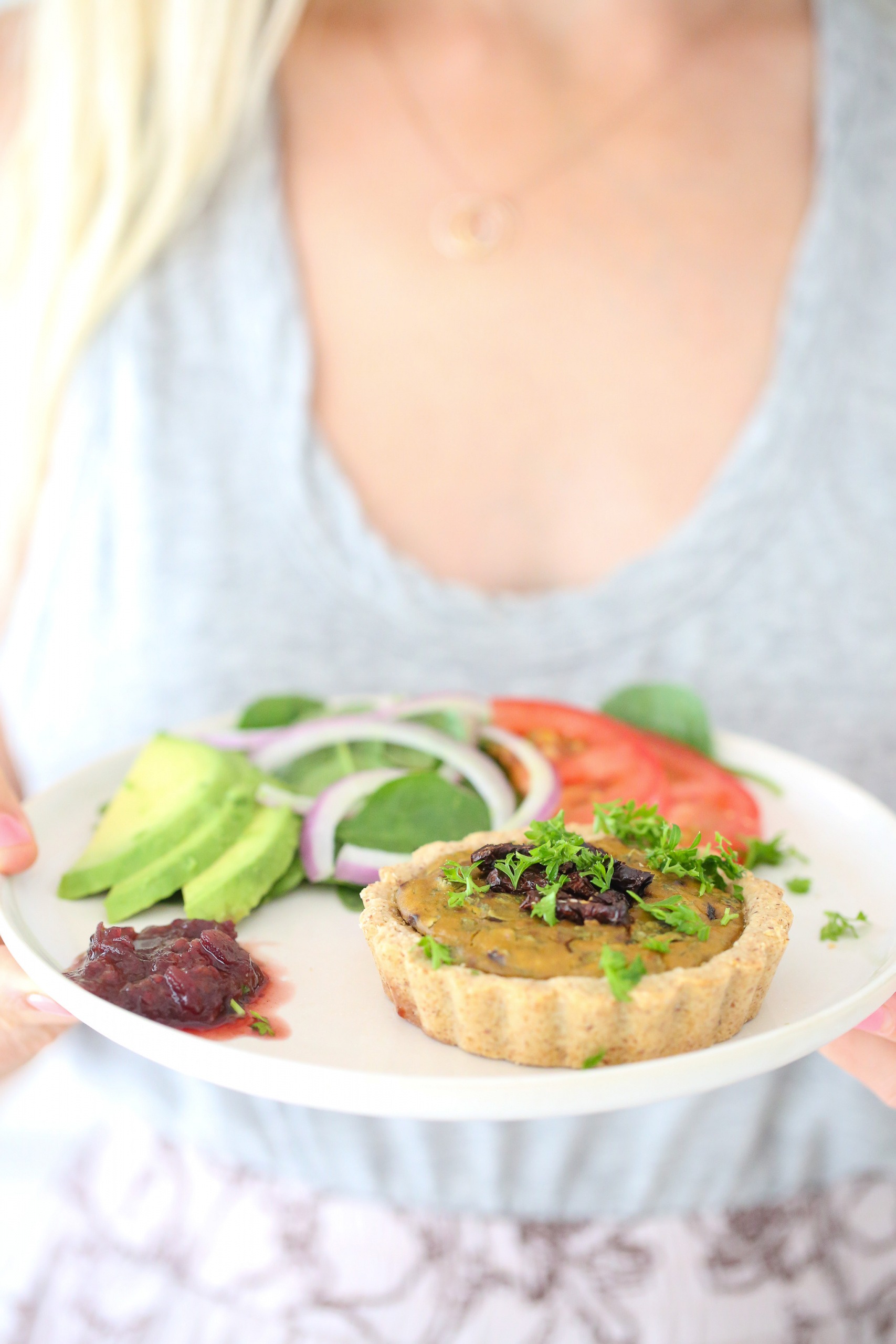 Vegan mini quiche topped with relish, parsley, salad, red onion, tomato, and avocado