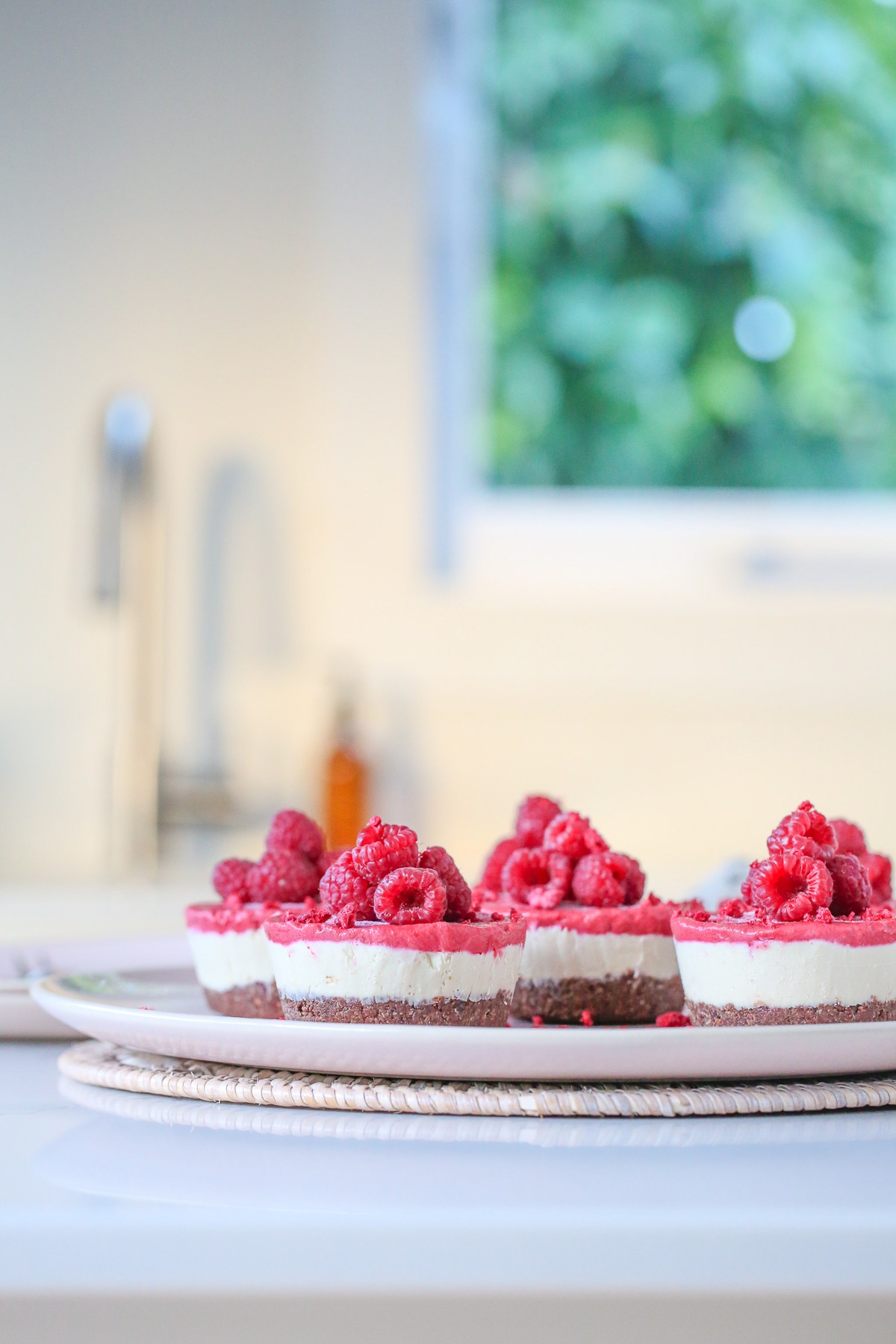 Close up of red and white vegan cheesecakes sitting on a pink plate.