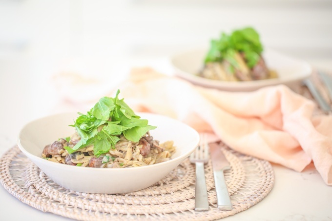 Creamy Mushroom Penne in a bowl with a handful of rocket on top. 