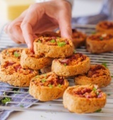 Pile of cheese, tomato and onion scrolls on a baking rack