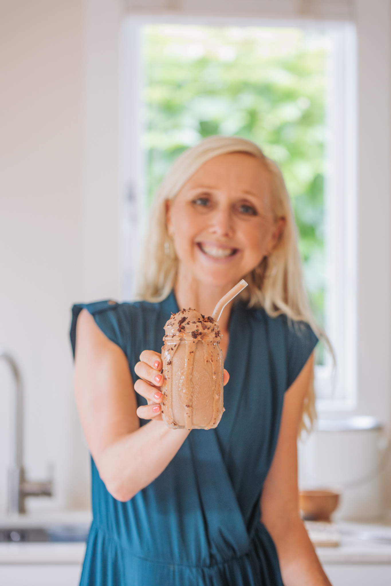 Buffy Ellen holding a milkshake with glass straw and cacao nibs in mason jar
