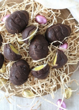 Chocolate caramel creme eggs on a board with straw and mini eggs