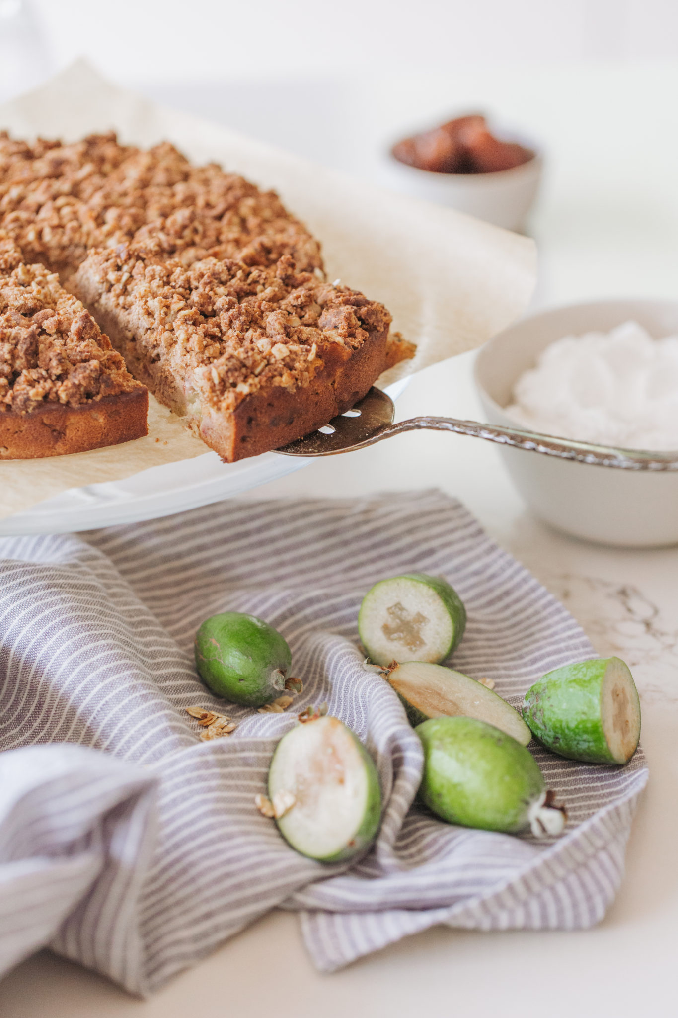 Feijoa Crumble Cake with dollop of coconut yogurt, sliced feijoa and stripped tea towel