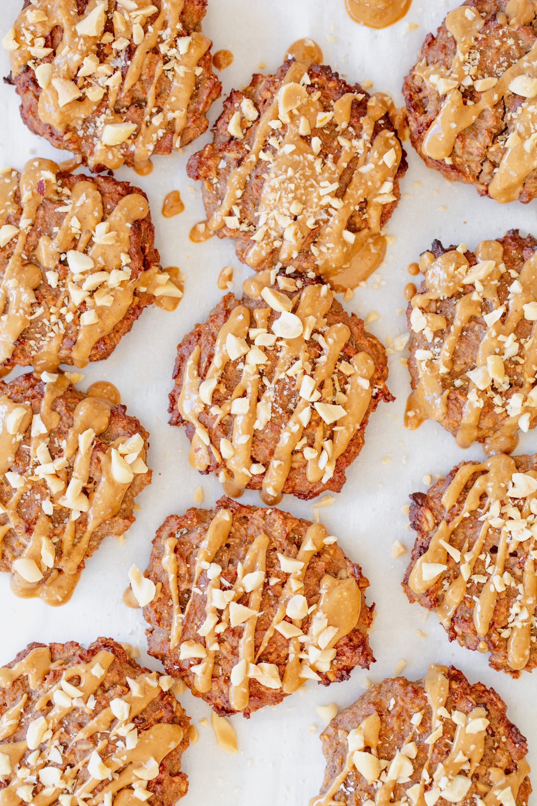 Close up of a tray of cookies with peanut butter drizzle and chopped roasted peanuts