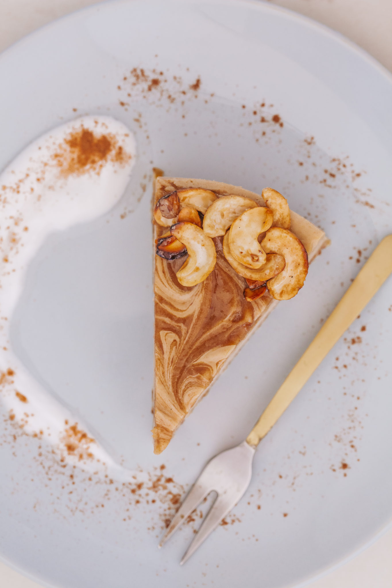 Caramel Rooibos Cheesecake on a blue plate with gold fork, coconut yoghurt swirl, and cinnamon