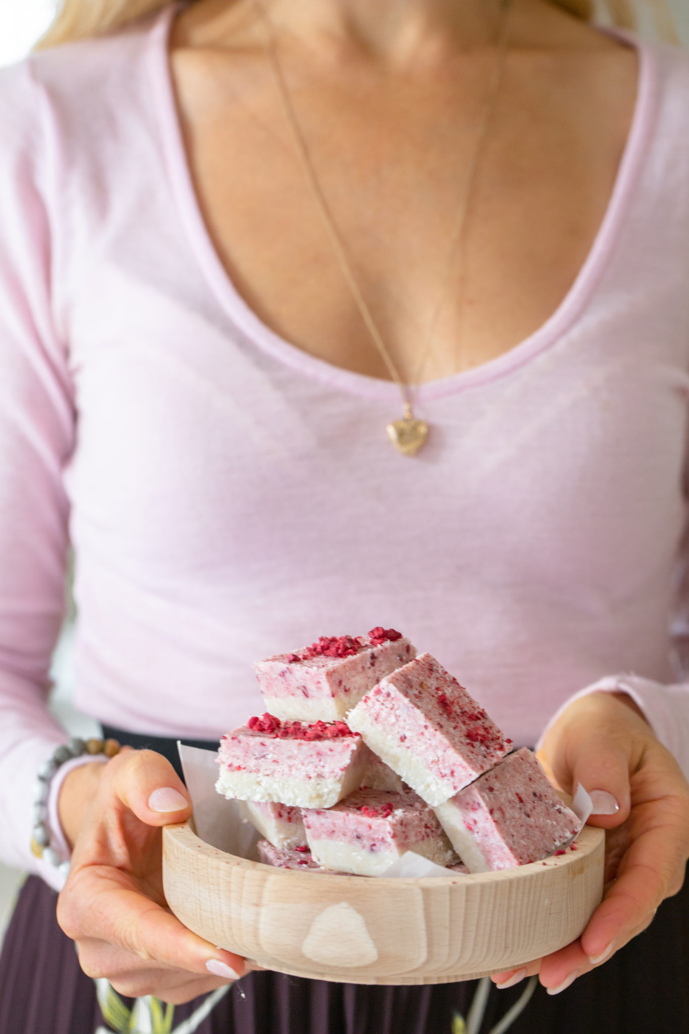 girl holding bowl with pink and white squares of coconut ice