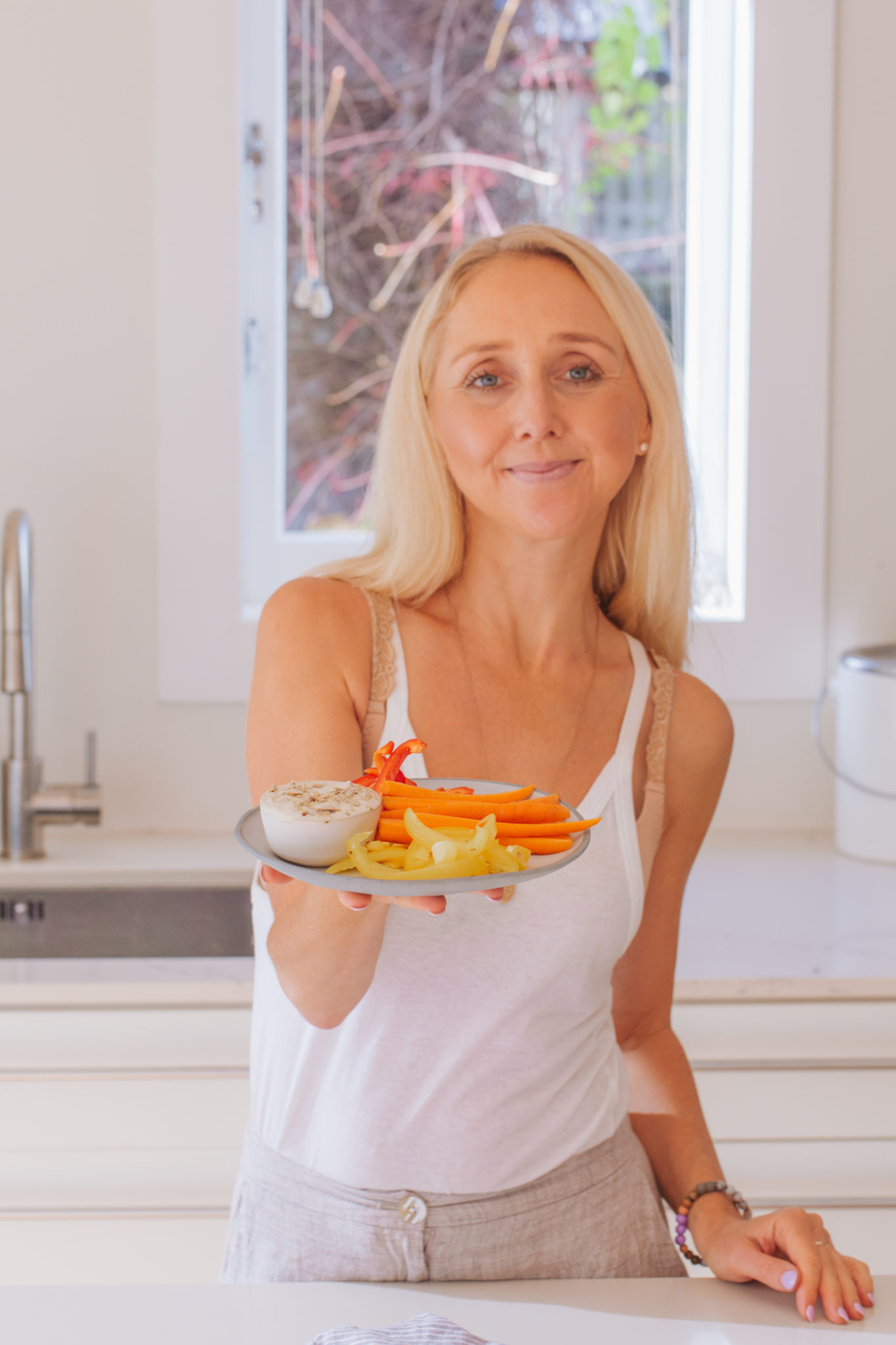 Buffy woman holding a plate with fresh vege and aioli