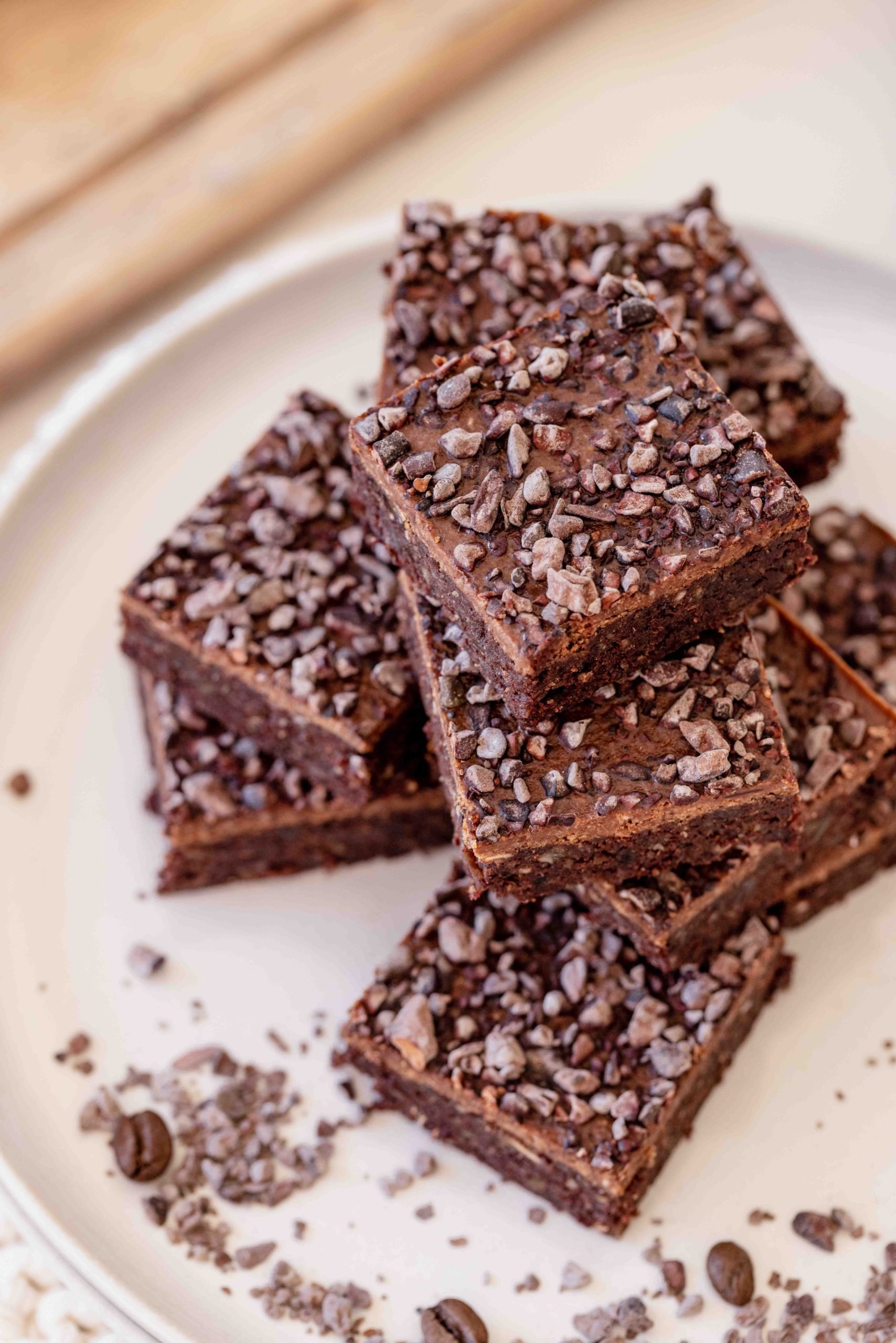 raw walnut espresso brownies with almond ganache and cacao nibs on white plate