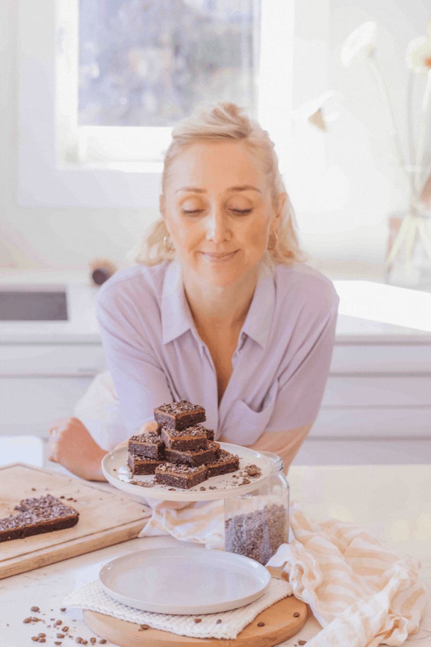 gif of Buffy Ellen holding raw walnut  espresso brownies with almond ganache and cacao nibs on white plate