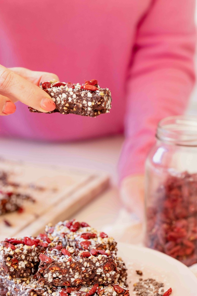 Buffy Ellen holding chocolate coated goji berries, buckwheat and coconut with pink nails