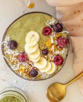 Matcha smoothie bowl topped with banana, berries, granola, and coconut